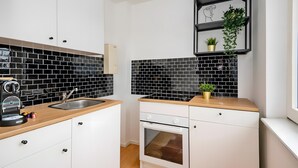 Una cocina moderna con baldosas blanco y negro, un lavamanos de acero inoxidable, horno empotrado y un estante pequeño con una planta.
