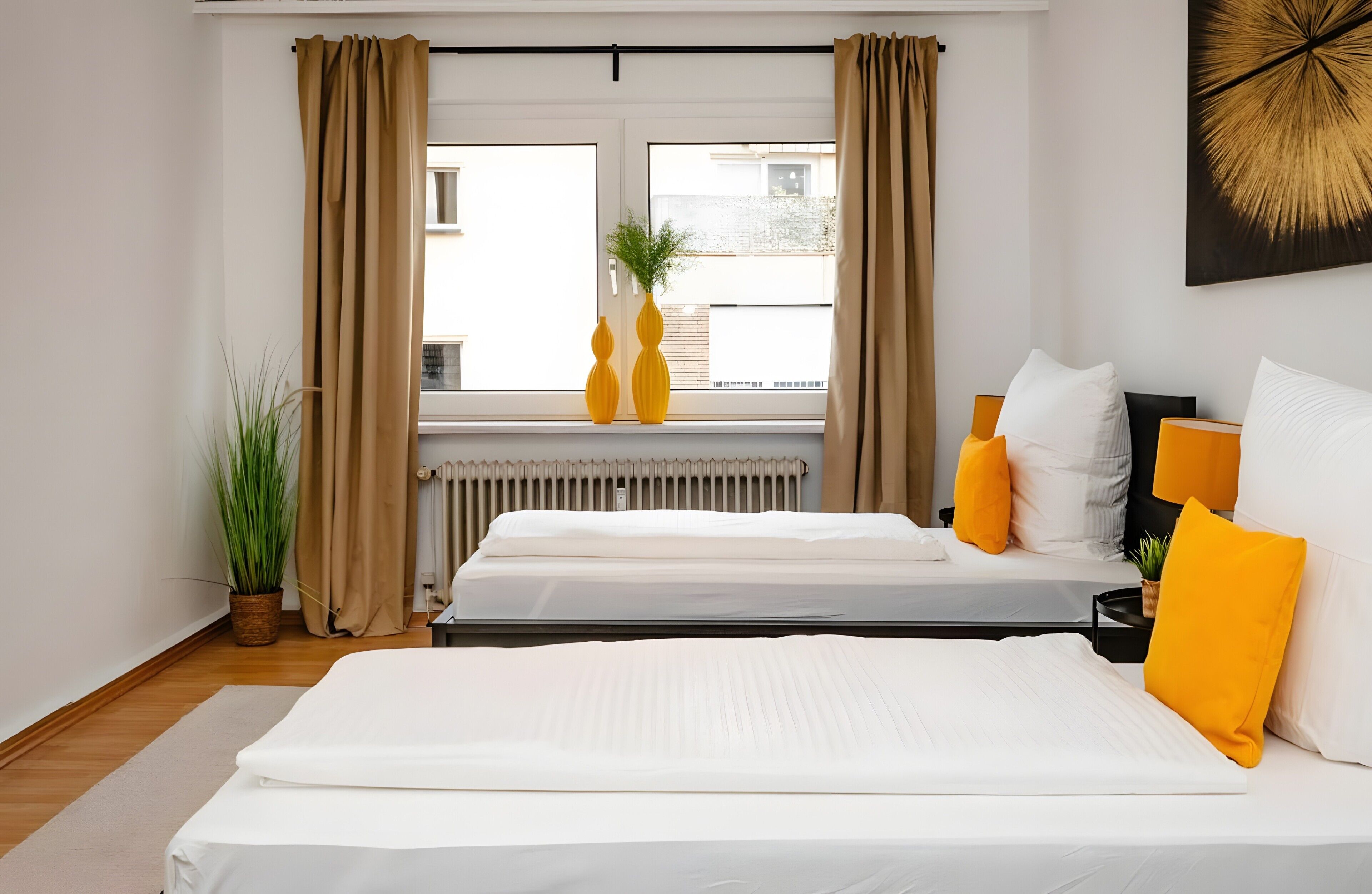 Une chambre d’hôtel avec deux lits, une fenêtre avec des rideaux, un radiateur et une plante.