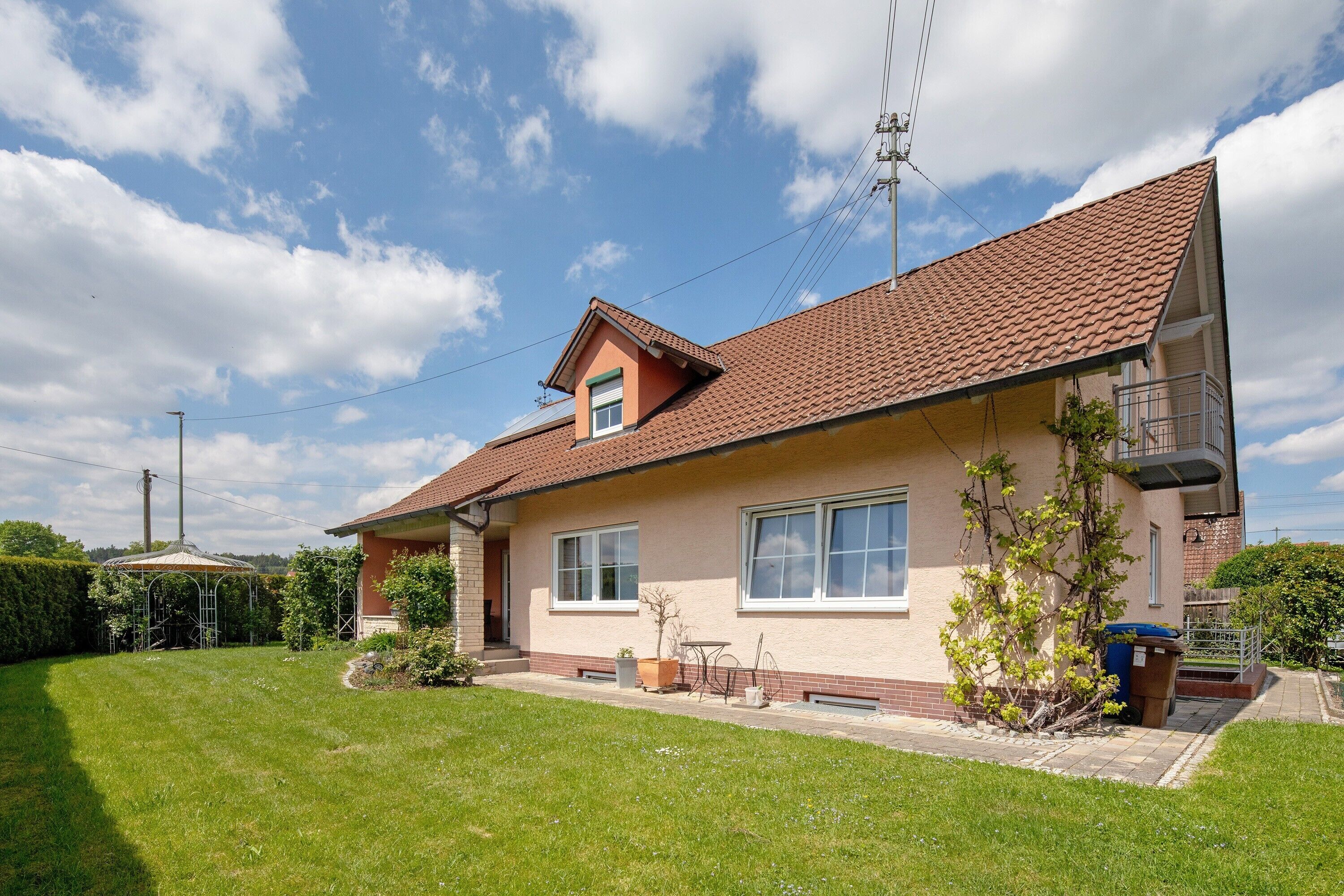 A single-story house with a tiled roof, a front porch, and a small garden area.
