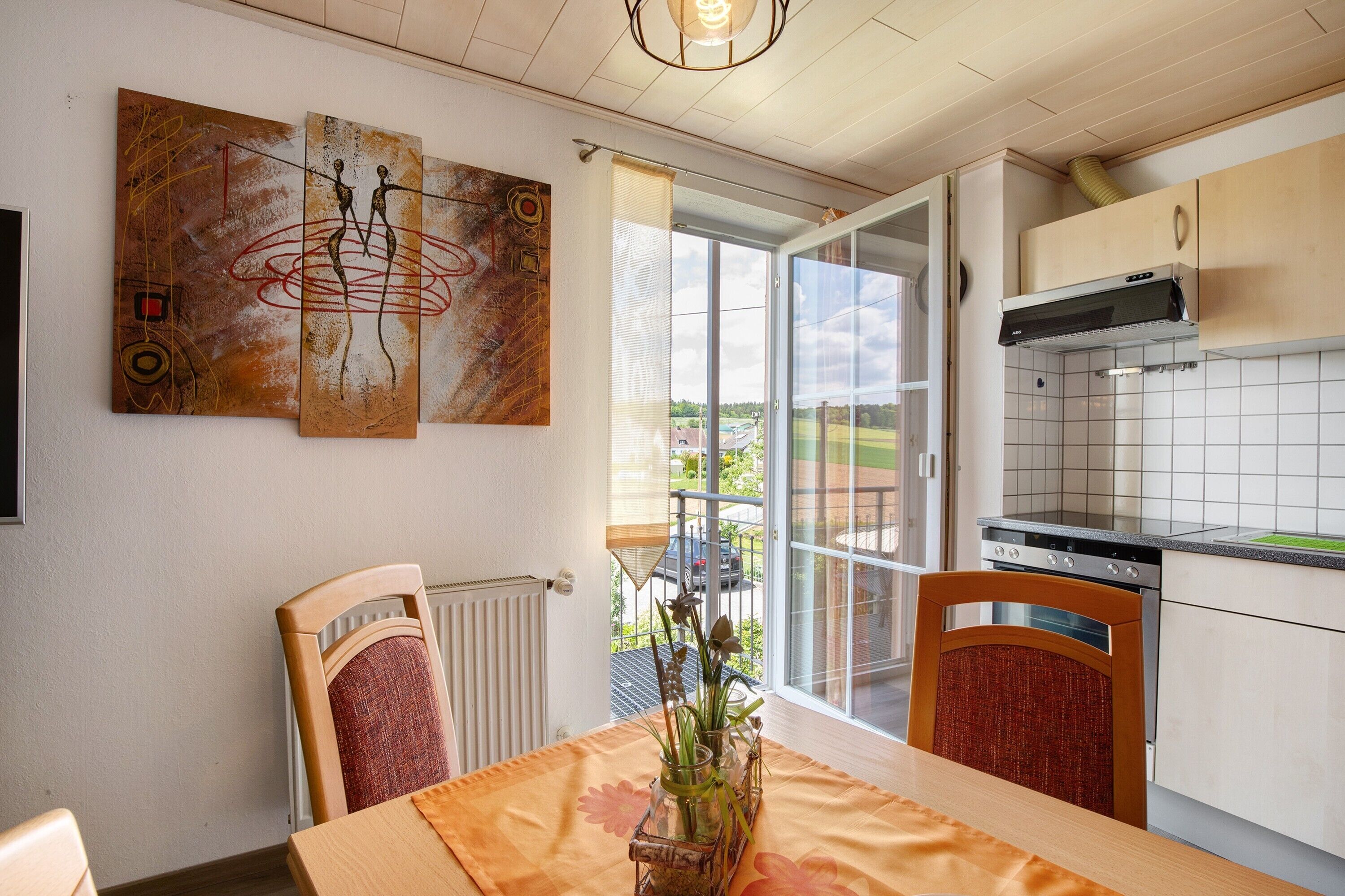 Una cocina con una mesa de comedor, sillas, un radiador y obras de arte en la pared.