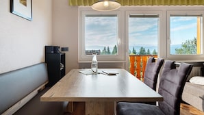 Ein Essbereich mit Holztisch, zwei Stühlen, einer Hängeleuchte und Blick durch die Fenster.
