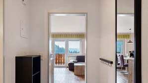 Ein Flur, der zu einem Balkon mit Aussicht führt, mit einer Couch, einem Tisch und einem Stuhl.