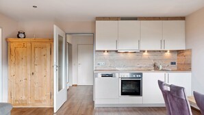 Eine moderne Küche mit weißen Schränken, einer Holztür und einem eingebauten Backofen.