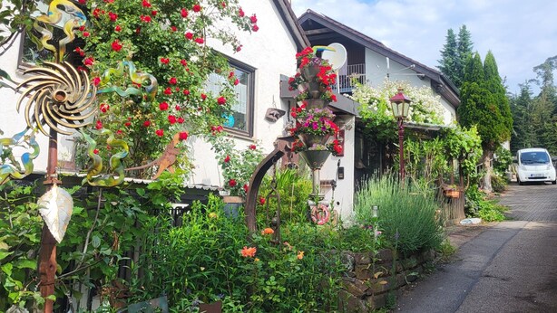 A white building with a garden, a metal sculpture, and a parked car. - Room 'Doppelzimmer Mit Balkon' with Balcony and Wi-Fi (Schömberg)
