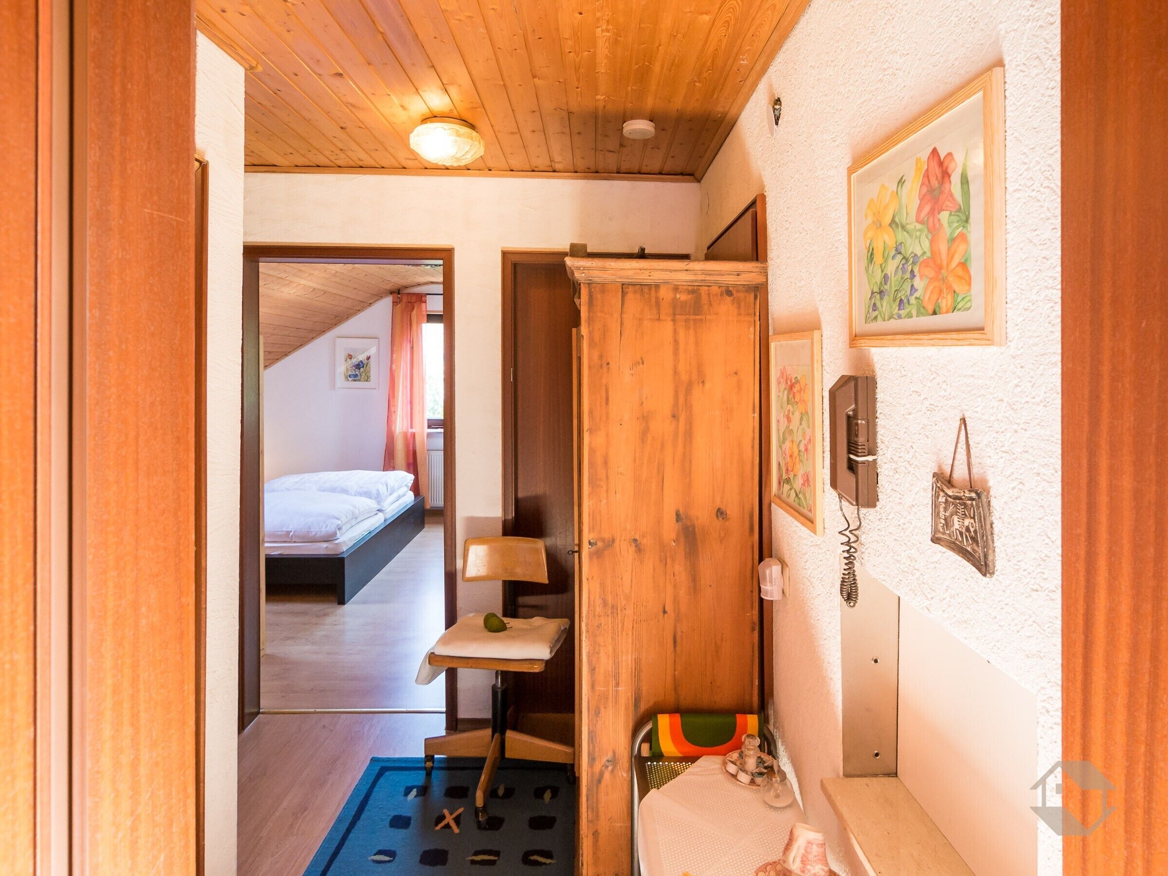 Une pièce comprenant un lit, une porte en bois, une petite table avec une chaise et un téléphone fixé au mur.