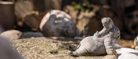 A stone sculpture of a dinosaur in a garden setting.