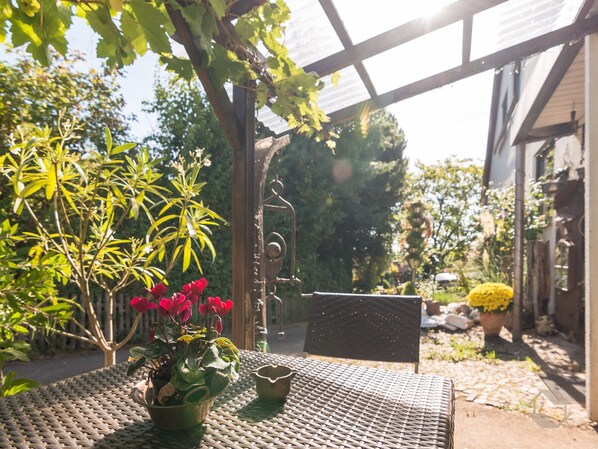 Un espace extérieur abrité, aménagé avec une table, des chaises et des plantes en pot.