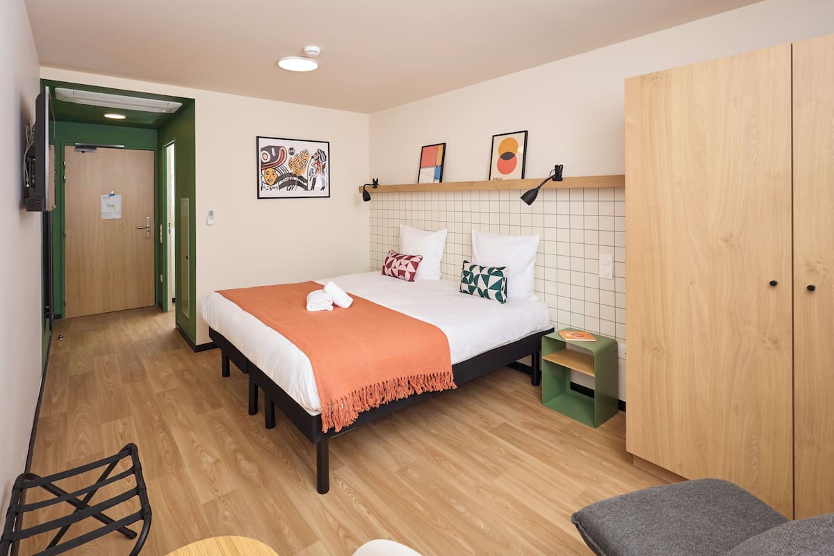 Une chambre à coucher avec un lit, une armoire, une étagère avec des photos et un banc vert.