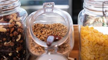 Three glass jars containing different types of granola on a wooden tray.
