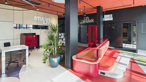 A modern workspace with a red and white color scheme, featuring a desk, chairs, and potted plants.