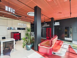 Un espacio de trabajo moderno con una decoración en tonos rojo y blanco, que incluye un escritorio, sillas y plantas en macetas.