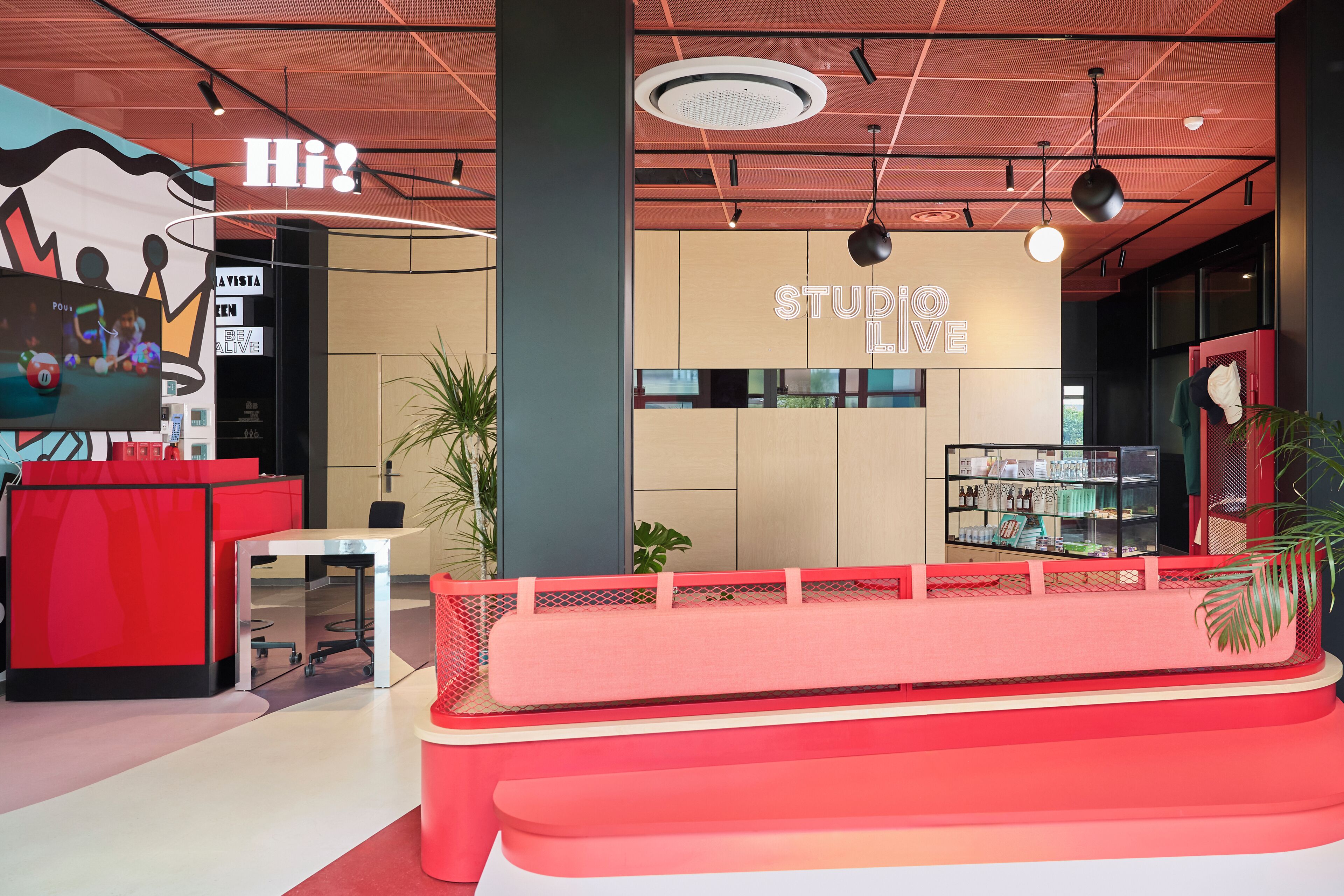 Un interior moderno con un mostrador de recepción, una zona de estar y una pared con el texto 'STUDIO LOVE'.