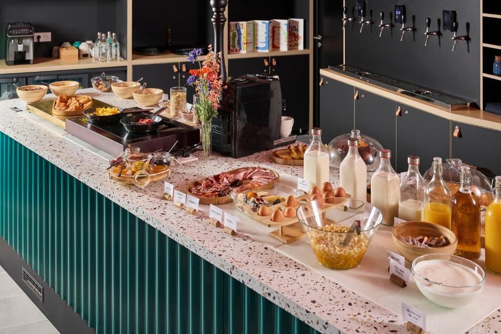 A buffet counter with various food items, beverages, and a coffee machine.