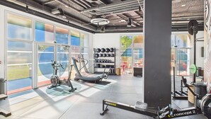 A gym with exercise equipment, large windows, and a view of the outdoors.