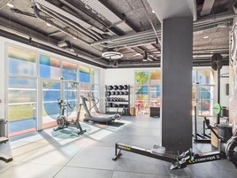 Un gimnasio con equipo de ejercicio, ventanas amplias y vistas al exterior.