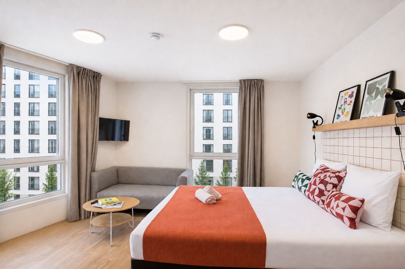 Een hotelkamer met een bed, een bank, een kleine tafel en twee ramen.
