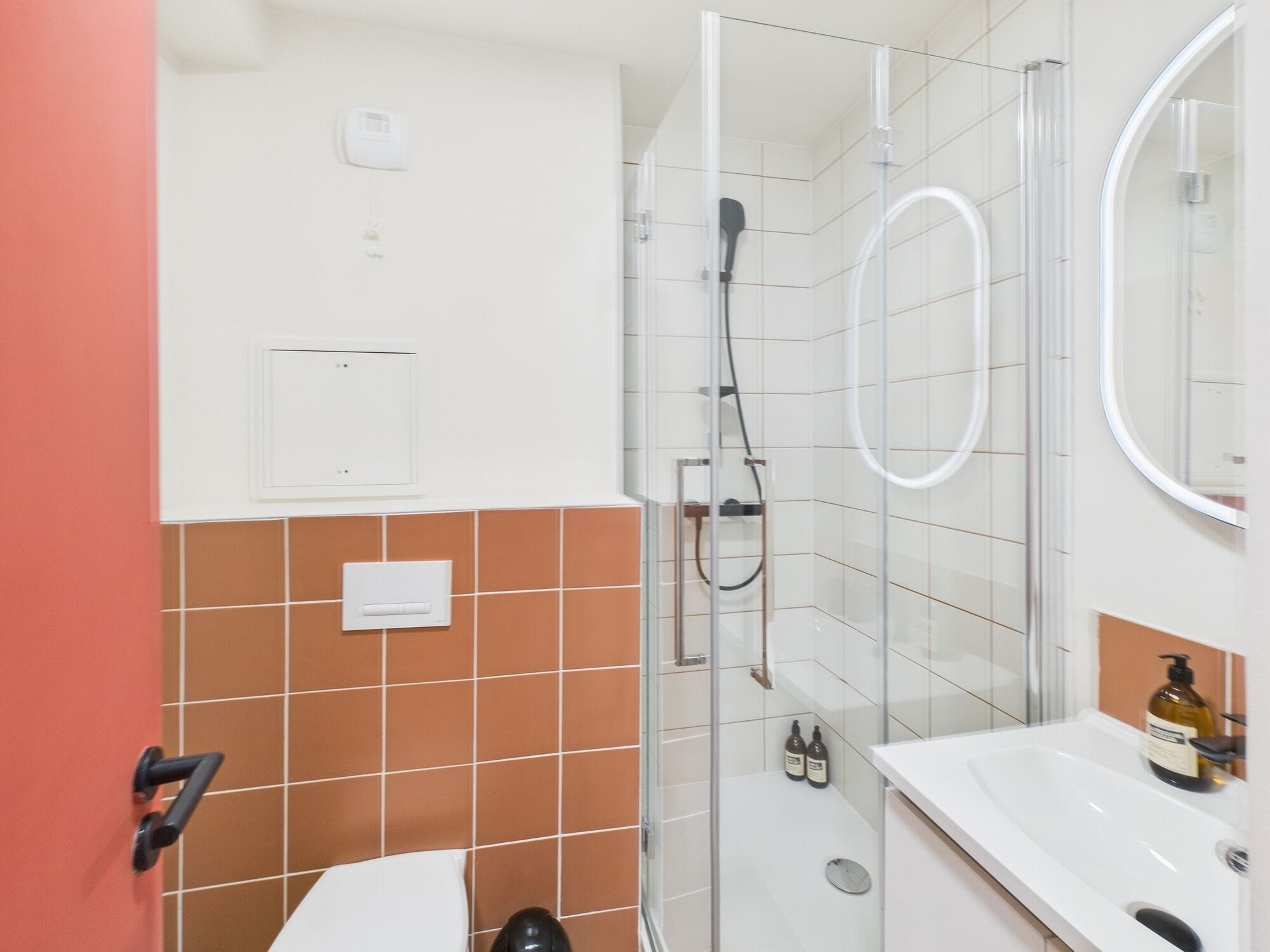 A bathroom with a glass shower enclosure, a white sink, and a mirror.