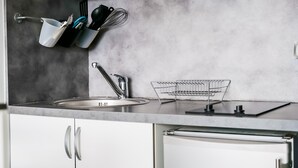 A modern kitchen with a stainless steel sink, a dish rack, and utensils hanging on the wall. - La Rose Des Vents - Studio - Arago - Sea View (Les Sables-d´Olonne)
