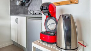 A compact kitchenette with a red coffee maker, a stainless steel kettle, and a small table. - La Rose Des Vents - Studio - Arago - Sea View (Les Sables-d´Olonne)