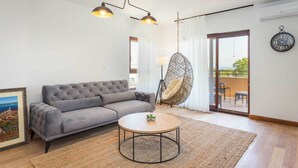A modern living room with a grey sofa, a round coffee table, and a hanging chair. - 4 guests apartment in Medulin (Ližnjan)
