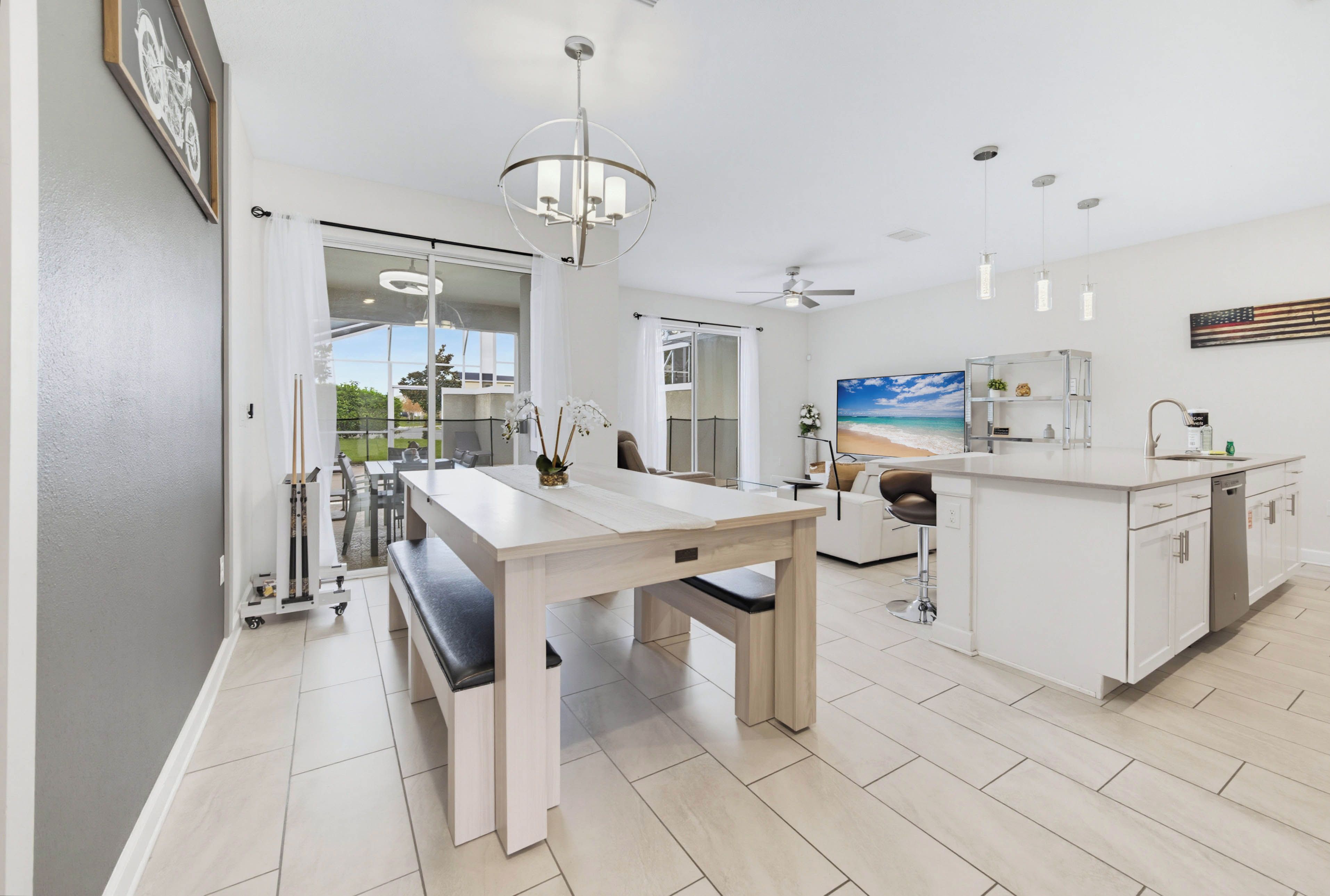 A modern kitchen with a dining area, a large window, and a ceiling fan.