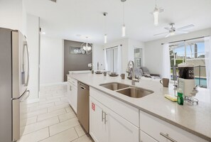 A modern kitchen with a large island, stainless steel appliances, and a view of the outdoors.