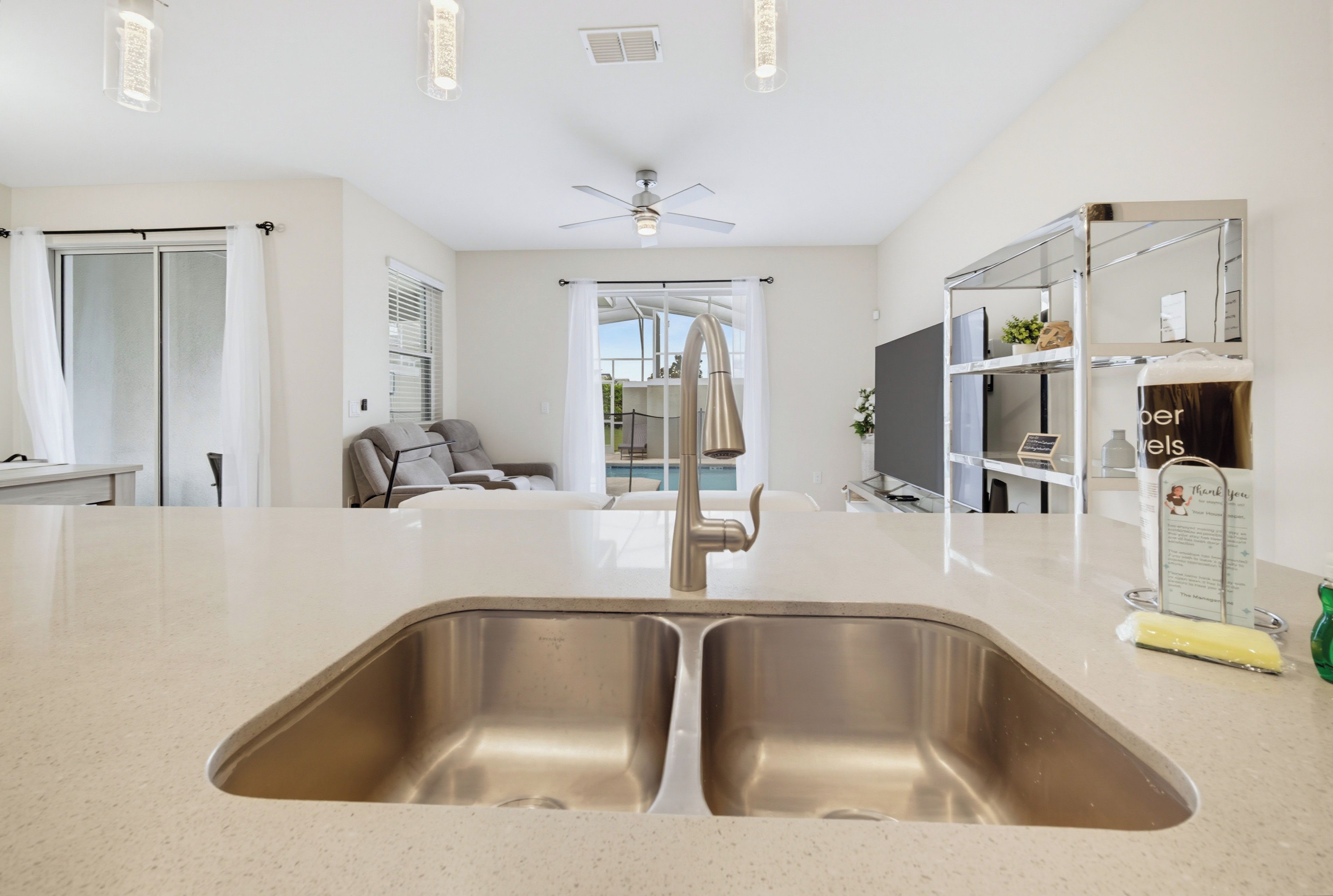 A modern kitchen with a double sink, a ceiling fan, and a view to the outside.