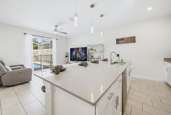 A modern kitchen with a large island, a dining area with a sofa, and a view of a swimming pool.