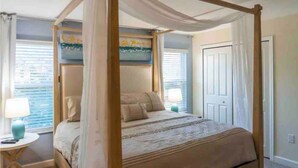 Una cama con dosel, una mesita de noche con lámpara y una ventana con persianas.