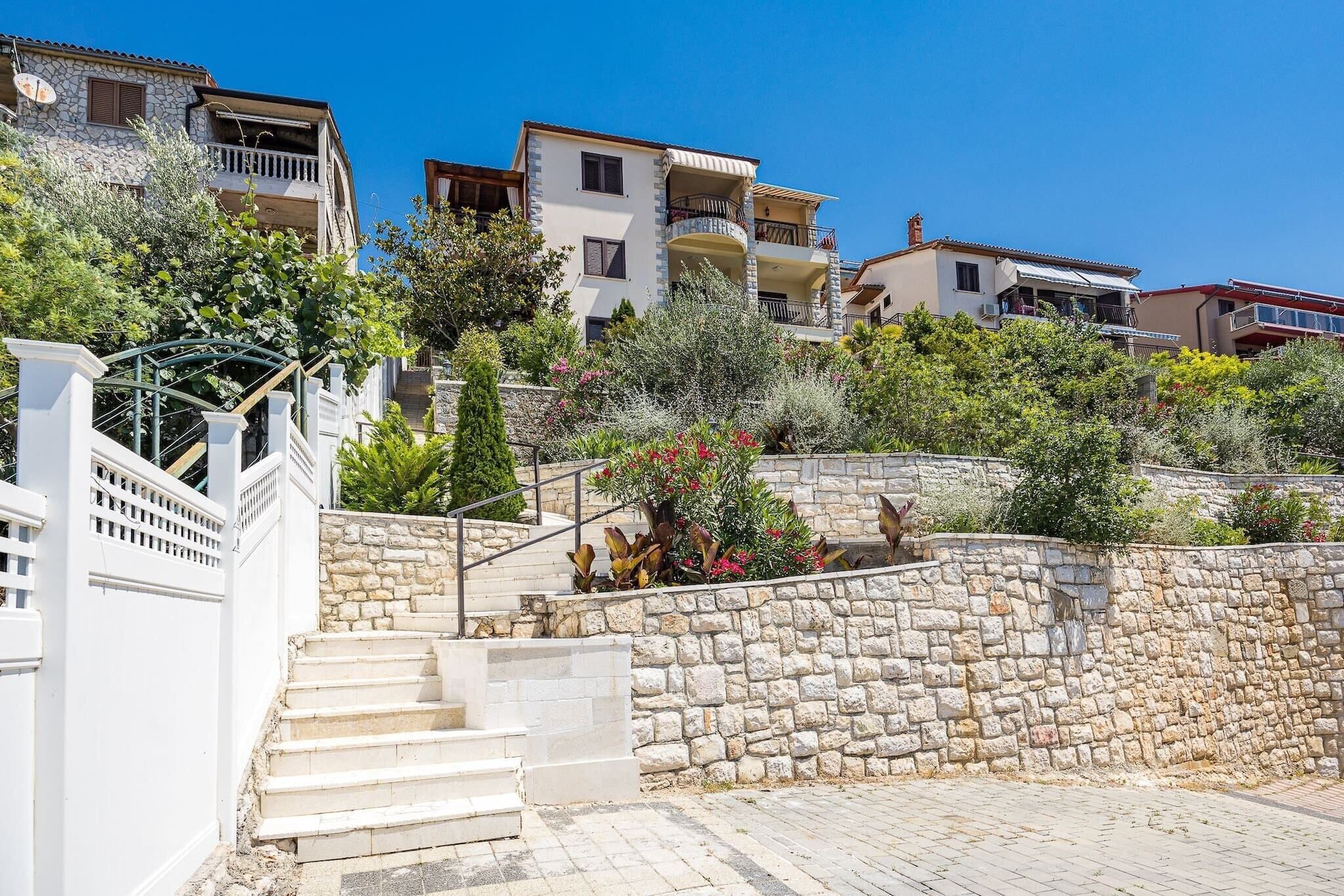 A residential area with stone steps leading up to a white building with balconies.