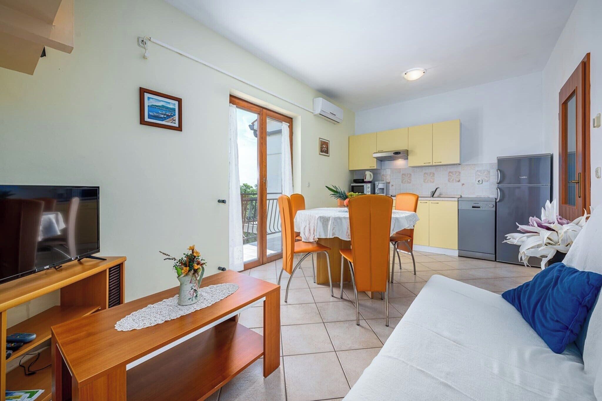 Un espace de vie compact comprenant un téléviseur, une table à manger et une kitchenette.