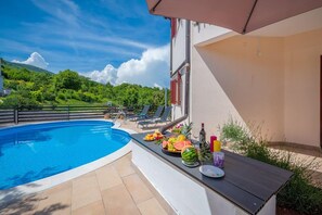 A swimming pool with lounge chairs and a table with fruits and drinks.