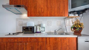 A modern kitchen with wooden cabinets, a built-in oven, a coffee maker, and a sink.