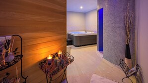 A spa area with a wooden wall, a massage table, a massage chair, and a small table with candles.