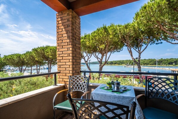 A balcony with a table and chairs overlooking a marina and the sea.