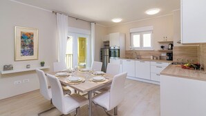 Una cocina moderna con armarios blancos, un refrigerador de acero inoxidable y una encimera de madera.