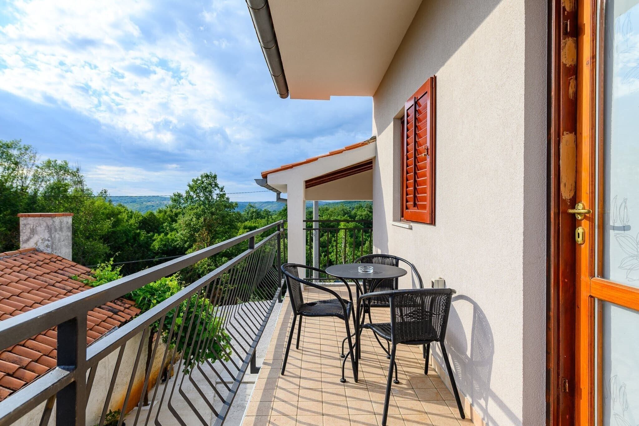 A balcony with a table and chairs, overlooking a scenic landscape.