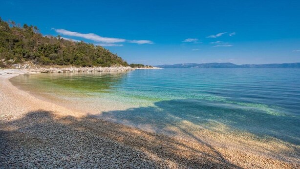 A pebbled beach with clear water and a forested hillside. - Spacious Apartment in Markoci (Markoci)