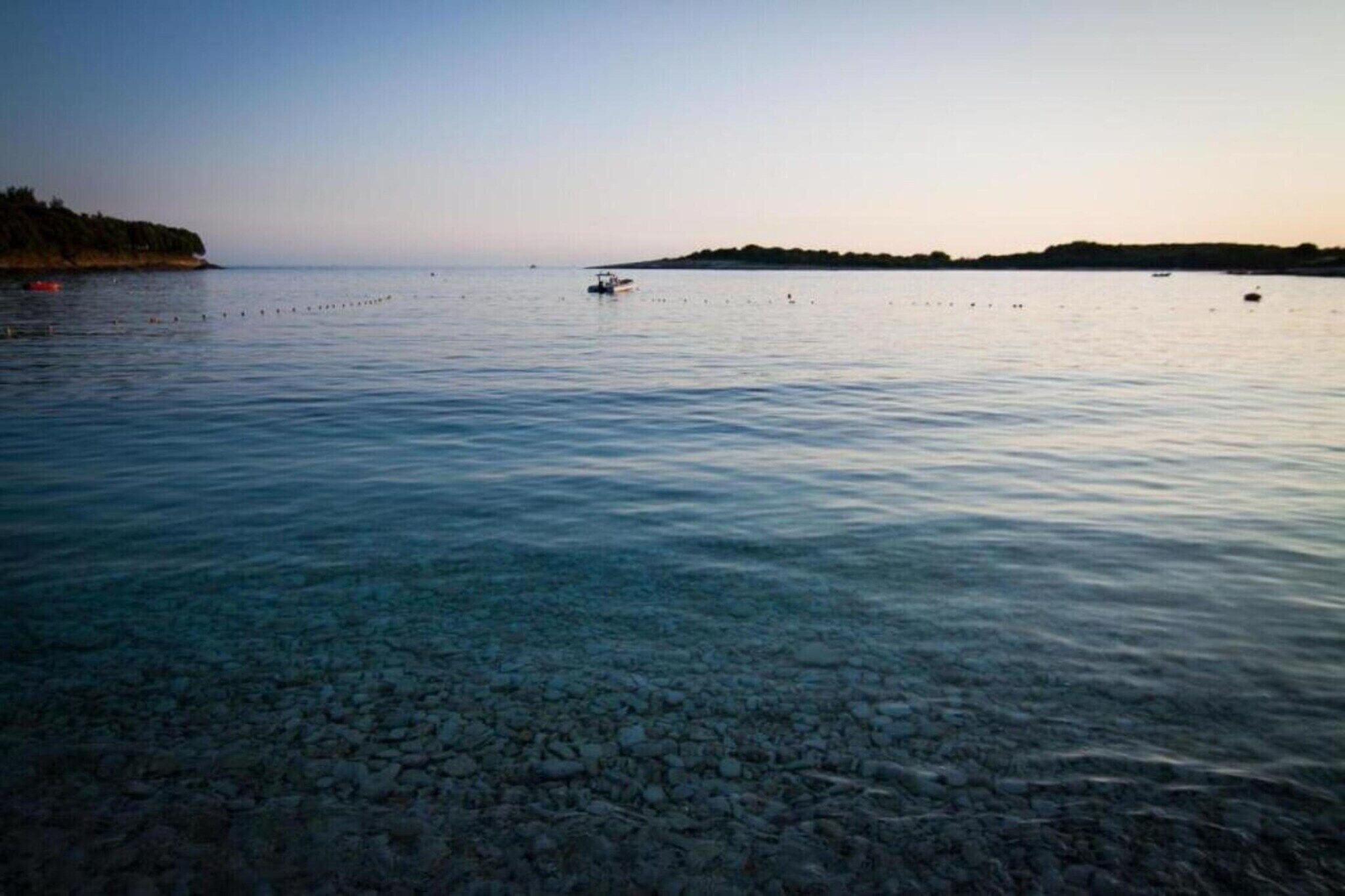 A calm body of water with a rocky shore and distant land.