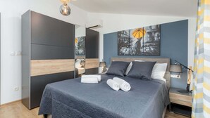 A modern bedroom with a large bed, a wardrobe, a nightstand, and a wall-mounted lamp.