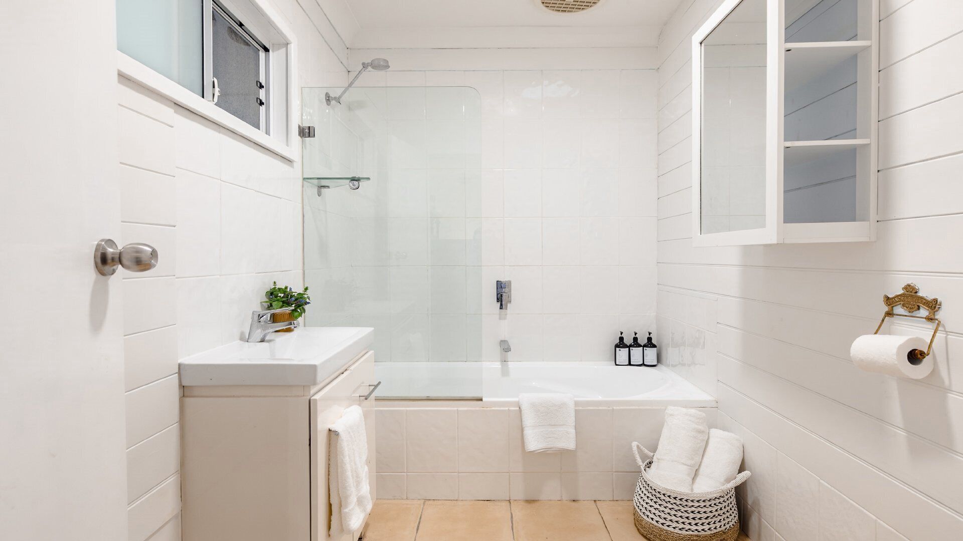 A modern bathroom with a bathtub, a glass shower enclosure, and a toilet paper holder.