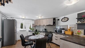 Une cuisine moderne dotée d’un îlot central, de chaises noires, d’un réfrigérateur et de divers appareils électroménagers.