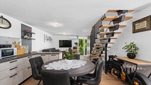 Une cuisine moderne avec un coin repas, un escalier au design original et une moto exposée.