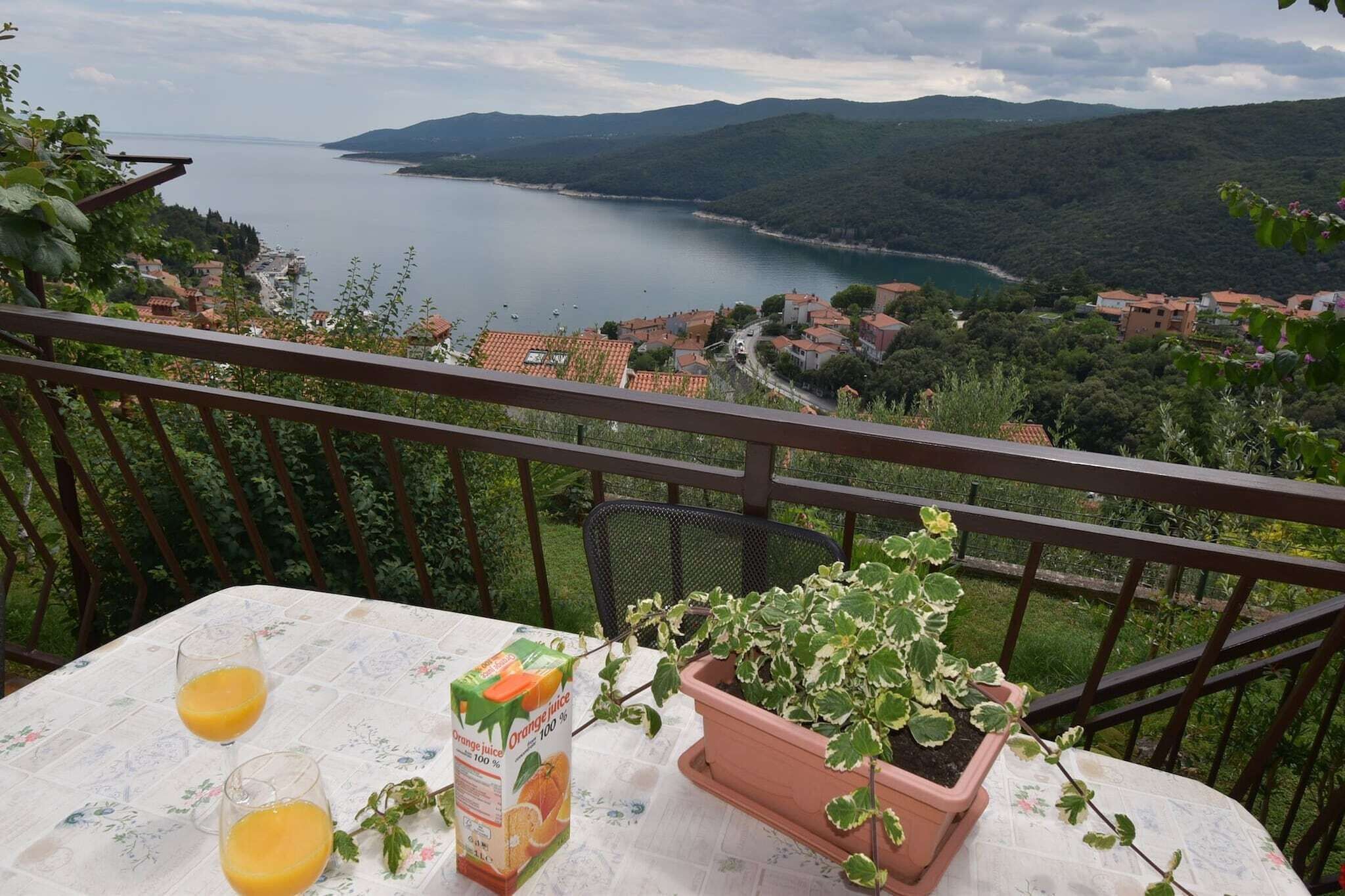 Ein Balkon mit Tisch, zwei Orangensaftgläsern und einem Blumentopf.