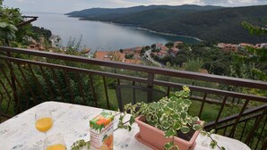 A balcony with a table, two glasses of orange juice, and a potted plant. - Cozy Apartment Near Beach (Rabac)