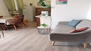 A living room with a grey sofa, a small round coffee table, and a dining area with a wooden table and chairs. - Cozy Apartment Near Beach (Rabac)