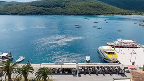 A coastal marina with boats docked, a ferry, and a café area with outdoor seating. - Cozy Apartment Near Beach (Rabac)