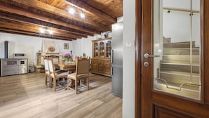 A kitchen with wooden flooring, a dining table with chairs, a refrigerator, and wooden cabinets. - Charming Villa with Pool (Nedešcina)