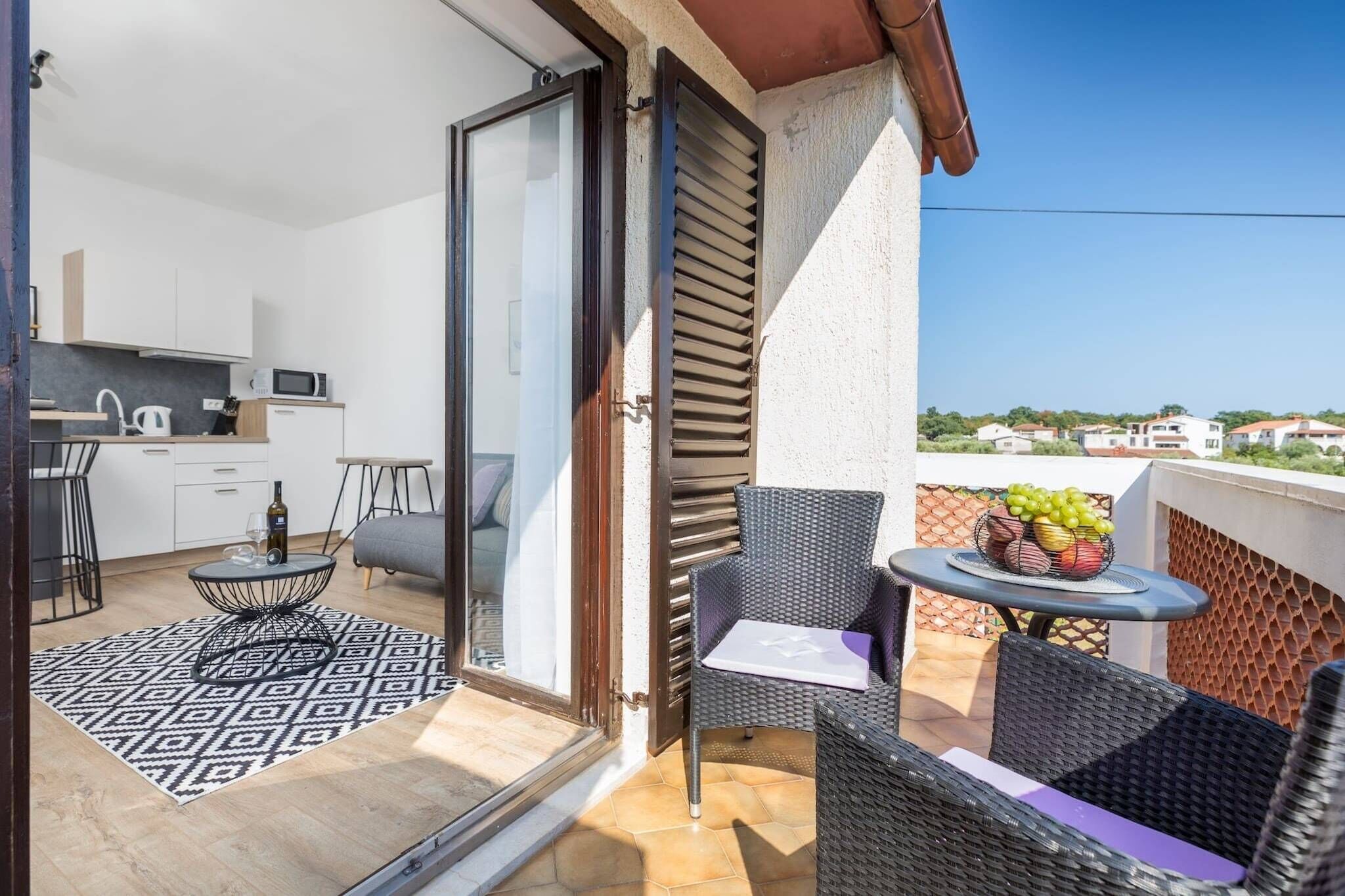 A balcony with a dining area, a kitchen, and a view of the neighborhood.