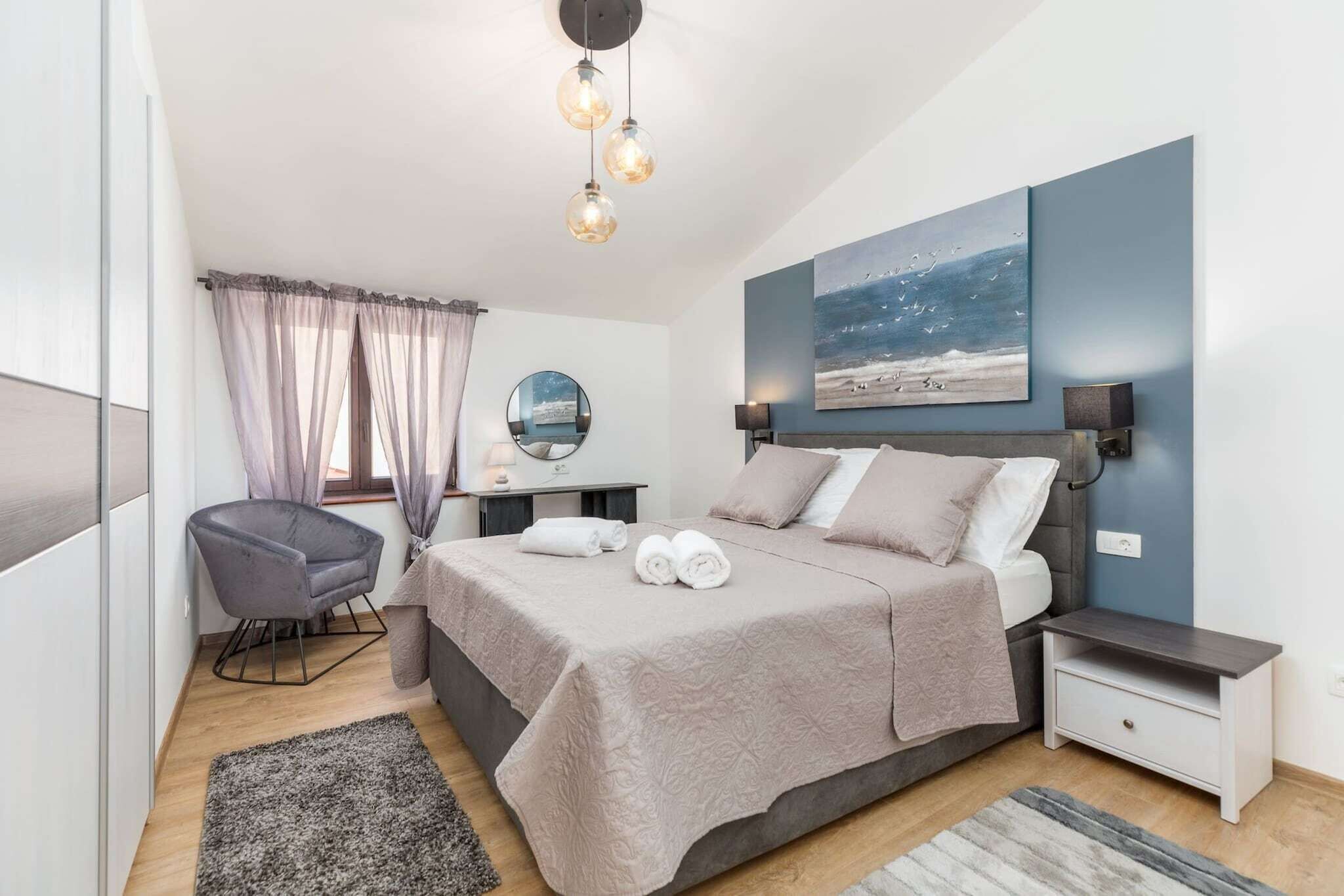 Une chambre à coucher moderne avec un grand lit, des tables de chevet, une chaise, un miroir et un tableau accroché au mur.